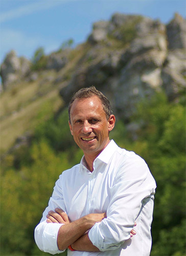 Das Bild zeigt Umweltminister Glauber vor einer Bergsilhouette