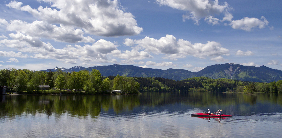 Zwei Personen in einem Faltboot auf einem See  vor der Bergkulisse der Bayerischen Alpen