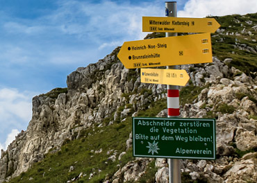 Das Bild zeigt Hinweisschilder an einem Bergpfad